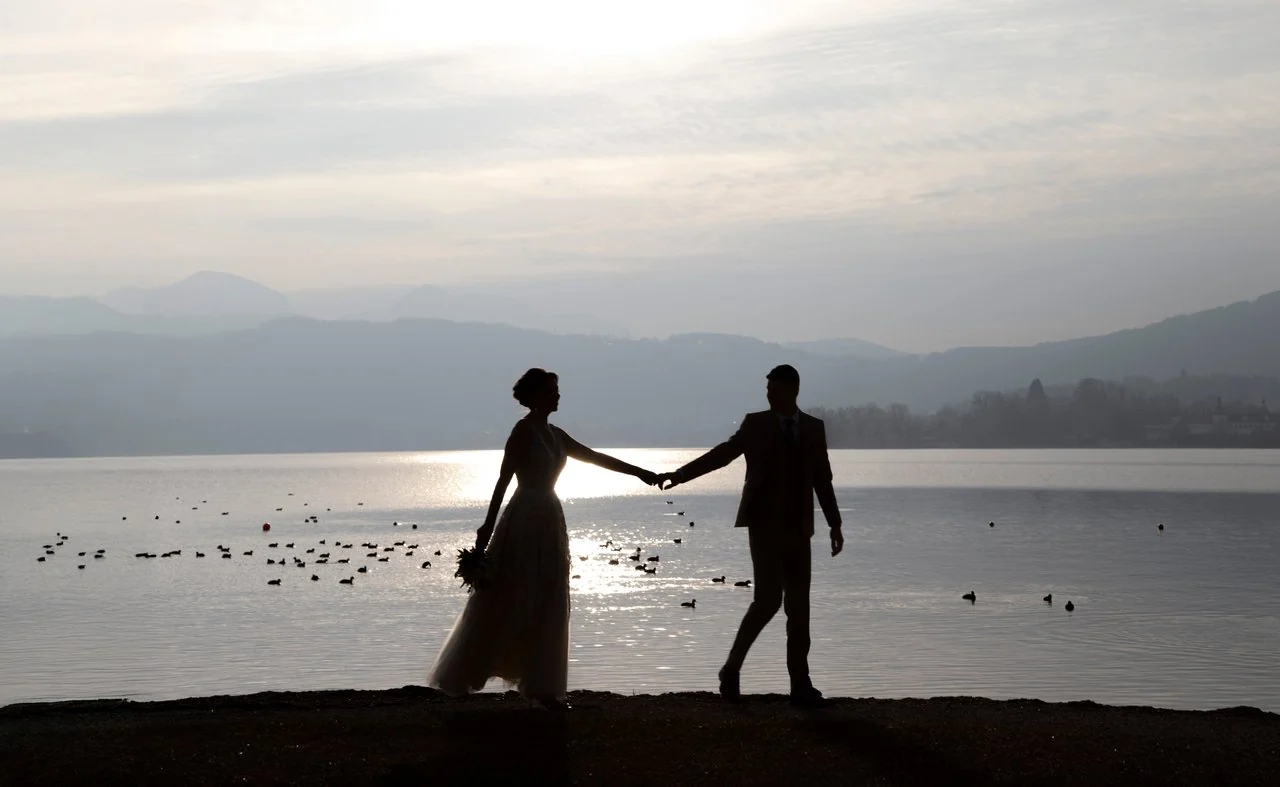 Silhouettes of a couple beside a lake